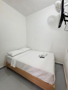 a white bedroom with a bed with white sheets at Hotel Jemara in San Gil
