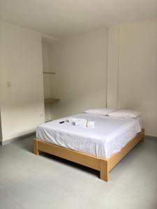a bed with white sheets and a wooden frame in a room at Hotel Jemara in San Gil