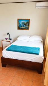 a bedroom with a bed with a blue blanket on it at Casa Amarilla Caribbean Stay in Puerto Limón +9 photos