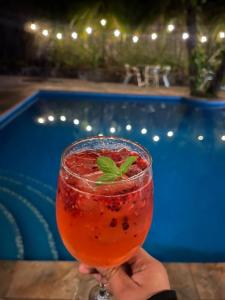 a person holding a drink in front of a pool at Hotel Camino Surreal Xilitla in Xilitla