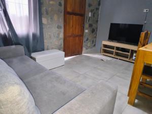 a living room with a couch and a television at Cabañas 2TIERRAS in Chicoana