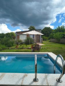 a swimming pool in front of a house at Cabañas 2TIERRAS in Chicoana