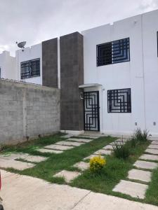 a white house with black windows and grass at Casa Morelia ideal, rest or work in San Carlos