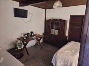 a bedroom with a bed and a table and a desk at Pousada Pindobas in Venda Nova do Imigrante