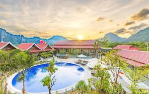 a resort with a pool and mountains in the background at Sunset Mountain View Resort in Vang Vieng