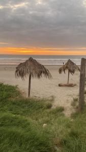 two straw umbrellas on a beach at sunset at Negritos Beach House in Negritos