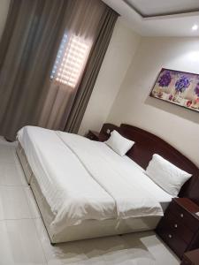 a bedroom with a large white bed in front of a window at شقق فندقيه in Buraydah