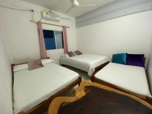 a room with three beds and a window at Hotel La Cima in Arboletes