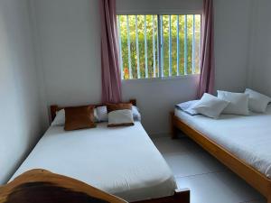 two beds in a room with a window at Hotel La Cima in Arboletes +6 photos