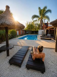 チャスコムスにあるApart Hotel Las Moraditas - a 50 metros de la Lagunaのプールサイドのベンチに座っている女性