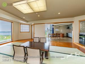 a dining room and living room with a table and chairs at YU-FURI Izukogen in Ito