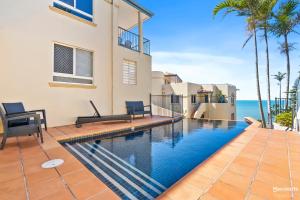a swimming pool in front of a house with the ocean at Ocean View Villa in Yeppoon