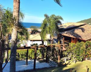 a view of a house with palm trees and the ocean at Residencial Hibiscos - Vista Mar in Garopaba