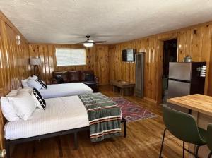 two beds in a room with wooden walls and wooden floors at Bellamy's Ski Haus in Red River