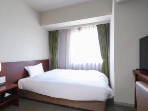 a hotel room with a bed and a window at Dormy Inn Himeji Natural Hot Spring in Himeji
