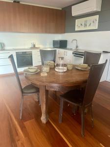 a wooden table in a kitchen with chairs around it at Your SHACK by the water in Sorell +2 photos