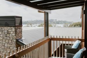 a balcony with two chairs and a stone wall at Dune View Accommodation in Mangawhai +10 photos