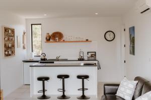 a kitchen with a counter and stools in a room at Dune View Accommodation in Mangawhai
