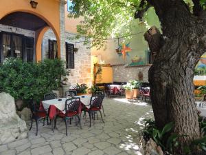 an outdoor patio with tables and chairs and a tree at Rooms Marko Polo in Zadar