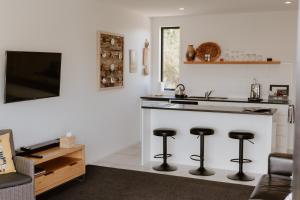 a kitchen with a counter with stools and a sink at Dune View Accommodation in Mangawhai