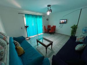 a living room with a blue couch and a table at شالية غرفتين بقرية ديمورا in Dawwār Muḩammad Abū Shunaynah