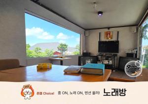 a living room with a table and a large window at Hoengseong Olympus Pension in Hoengseong