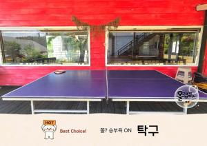 a ping pong table in front of a red building at Hoengseong Olympus Pension in Hoengseong