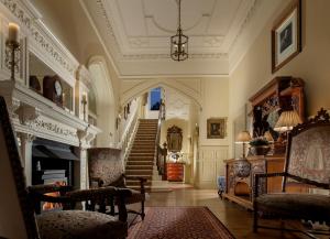 a living room with a fireplace and a staircase at Crossbasket Castle in High Blantyre