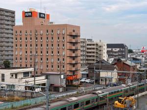 a train on the tracks in a city with buildings at APA Hotel Saitama Ageo-Ekimae in Ageo