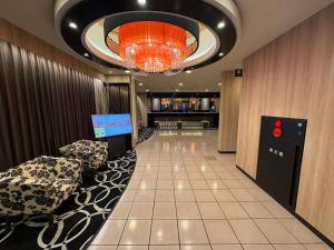 a lobby with two chairs and a chandelier at APA Hotel Saitama Ageo-Ekimae in Ageo