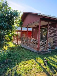 a red house with a grass yard in front of it at Cabañas Pakaia in Hanga Roa