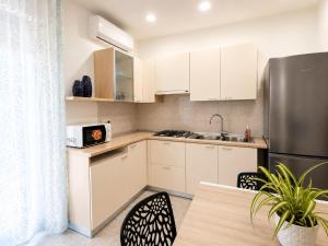 a kitchen with white cabinets and a stainless steel refrigerator at Center Room Tortolì wifi, AC, free parking, city center at 100 m in Tortolì