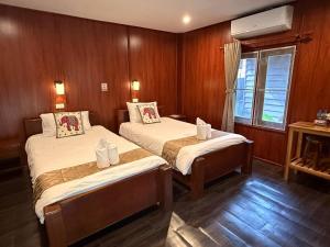 two beds in a room with wood paneling at D-Chu Mountain Haven Villas in Vang Vieng