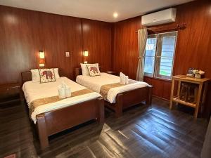 two beds in a room with wood paneling at D-Chu Mountain Haven Villas in Vang Vieng +4 photos