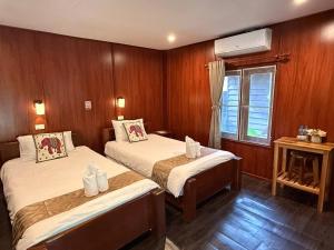 a room with two beds and a window in it at D-Chu Mountain Haven Villas in Vang Vieng