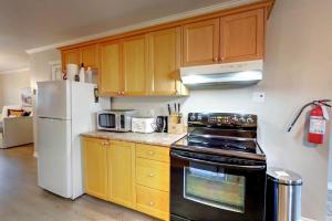 a kitchen with wooden cabinets and a white refrigerator at Wasaga Daze - Unit A in Wasaga Beach