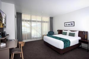 a hotel room with a bed and a desk and window at Quest Rotorua Central in Rotorua