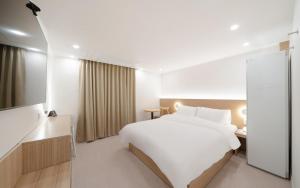 a hotel room with a large white bed and a television at MH Hotel 3 - Junghwasan in Jeonju +10 photos