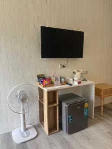 a small table with a television on a wall with a fan at Kanchana home stay กาญจนา โฮมสเตย์ สุราษฏร์ in Ban Bo Thong