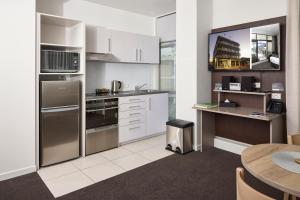 a kitchen with stainless steel appliances and a table at Quest Rotorua Central in Rotorua