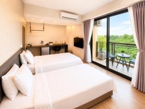 two beds in a hotel room with a balcony at Mo in Houli