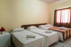 two beds sitting next to each other in a room at Pousada Aeroporto in Parnaíba