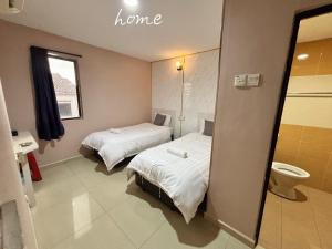 a room with two beds and a toilet in it at Happiness Hotel in Kulai