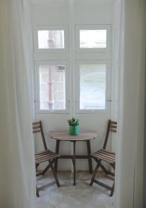 a table and two chairs in a room with two windows at No. 17 Birgu in Birgu