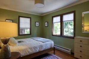 a green bedroom with a bed and two windows at Wanderwood in Guerneville
