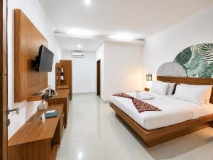 a bedroom with a large bed and a television at Eslem GuestHouse in Canggu