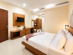 a bedroom with a large bed and a television at Eslem GuestHouse in Canggu