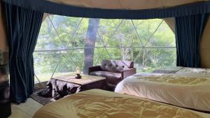 a room with two beds and a chair and a window at glampark Otaru Hanaemi Hokkaido in Otaru
