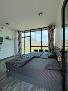 a large bed in a room with large windows at พิงภู ไทรโยค กาญจนบุรี in Sai Yok