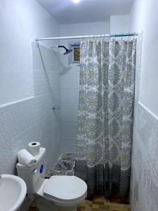a bathroom with a toilet and a shower curtain at Casa Miramar Tx in Trujillo